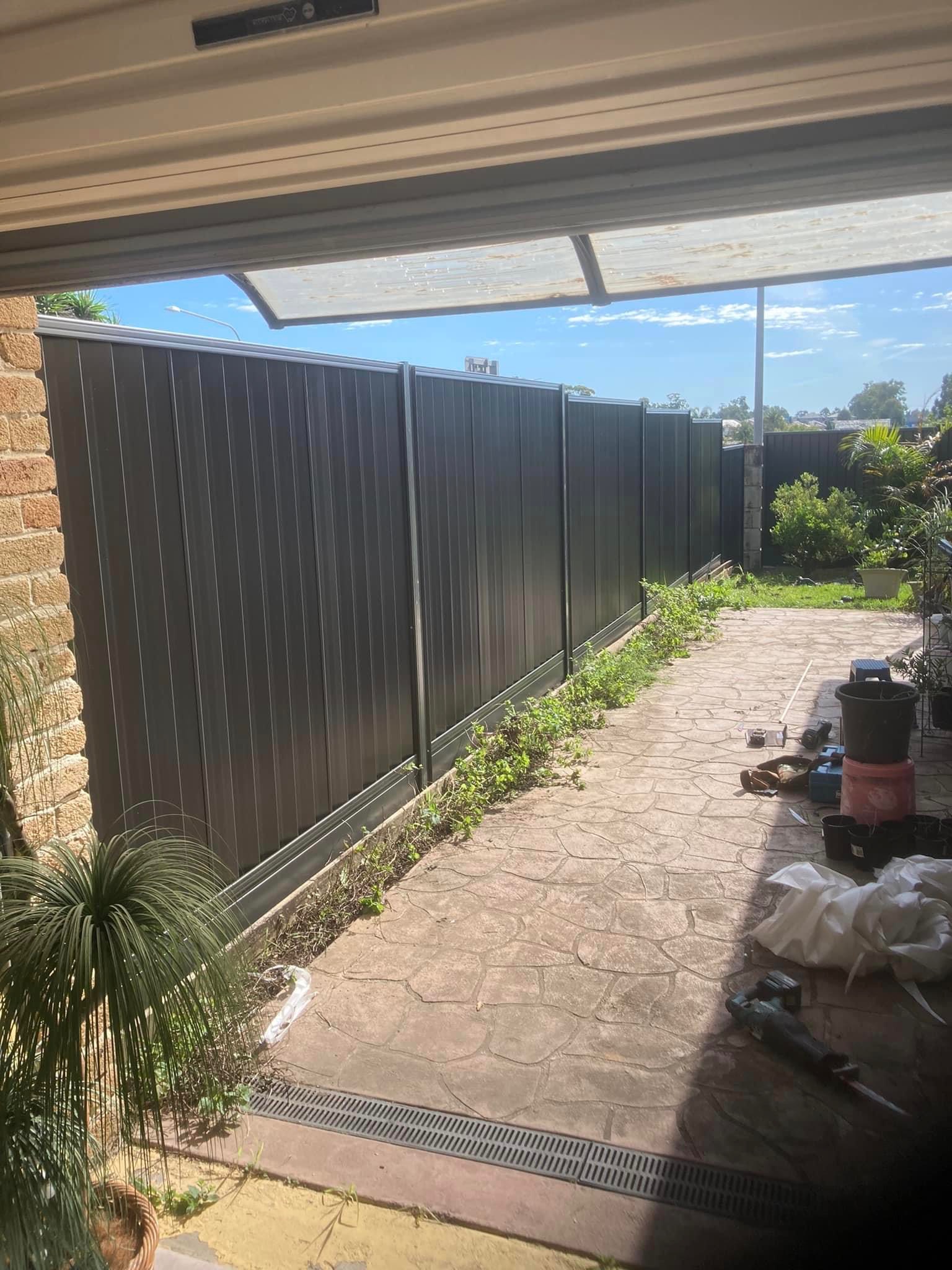 A charcoal Colorbond fence running down the side of a house