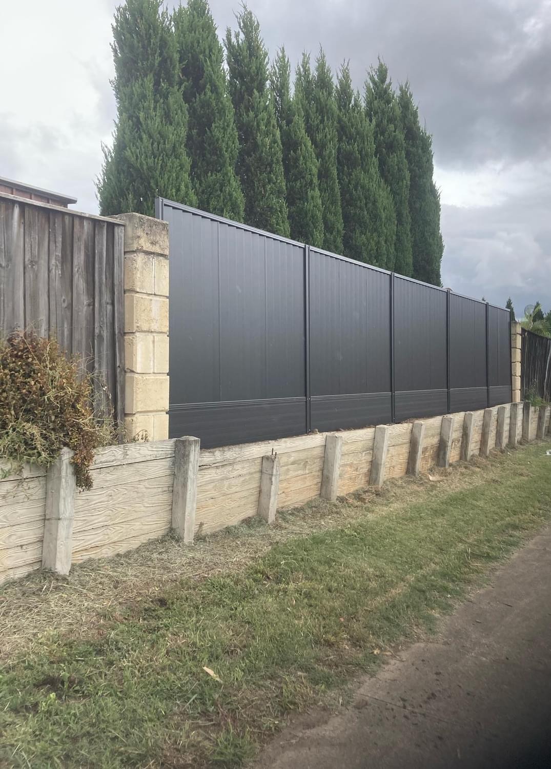 A long charcoal Colorbond run sitting on a concrete sleeper retaining wall