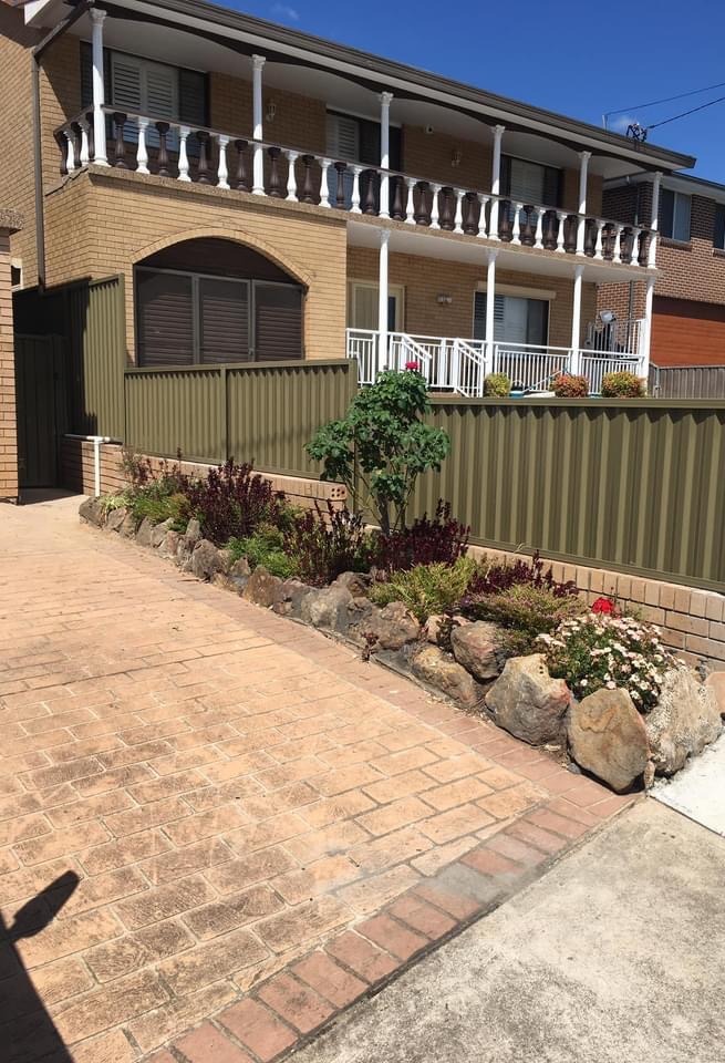 An olive Colorbond front fence above a planted garden bed