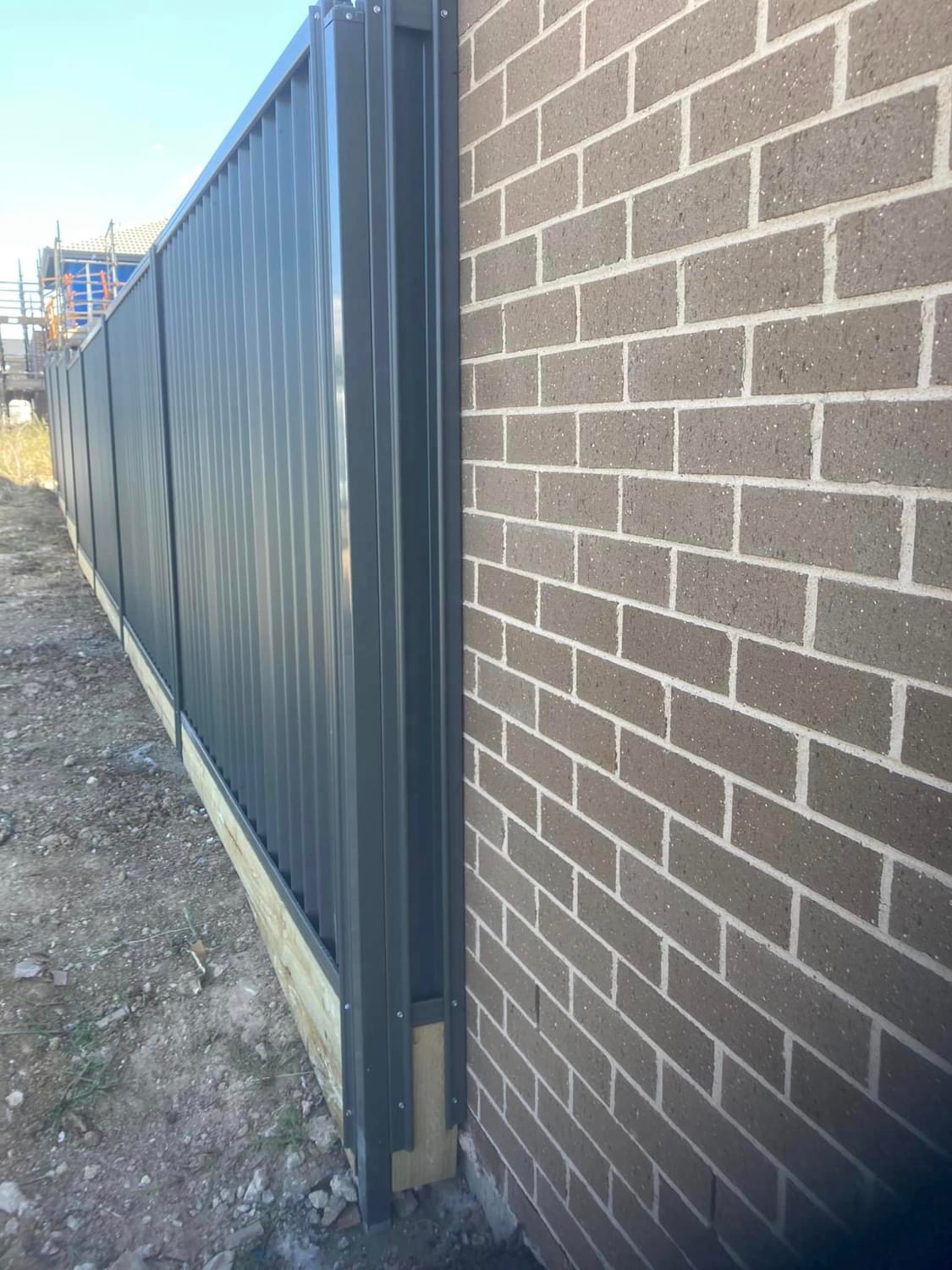 Close detail of a charcoal Colorbond panel finishing neatly against a brick wall